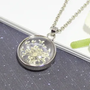 Close-up of white dried flower preserved in clear glass ball pendant necklace detail