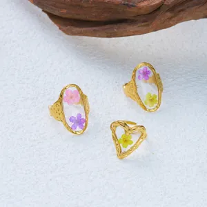 Detailed view of handmade resin rings with colorful dried flowers and hammered gold texture