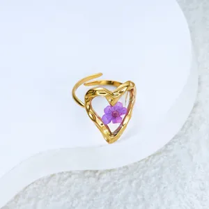 Detailed close-up of a golden hammered heart ring with a purple dried flower.