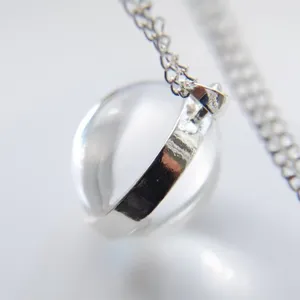 Macro detail view of a clear glass ball pendant with silver plated 925 stamped band