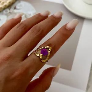 Macro view of a gold-plated heart ring featuring a real purple dried flower in resin