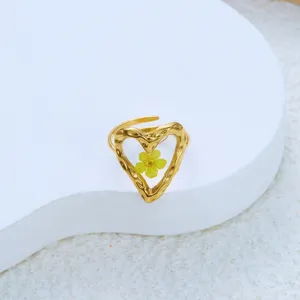 Macro view of gold stainless steel heart ring featuring a yellow dried flower in resin
