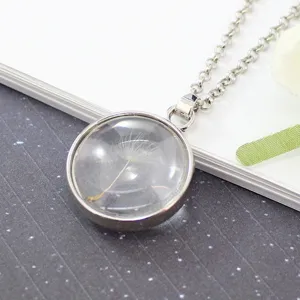 Detailed macro shot of a real dandelion seed preserved in a clear round glass pendant