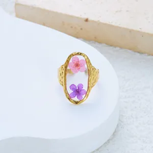 Detailed view of an open stainless steel ring with resin dried flowers and hammered texture.