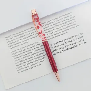 Close-up of elegant red dried flower floating ballpoint pen with rose gold trim