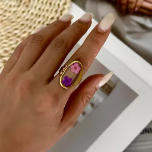 Detail shot of vintage gold-tone ring with real pink and purple dried flowers in resin.