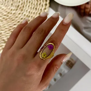 Close-up detail of a vintage stainless steel resin ring with purple and yellow dried flowers