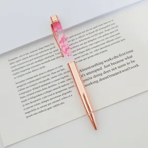 Close-up of rose gold metal ballpoint pen featuring elegant dried flowers in oil