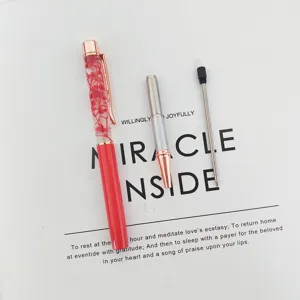 Detailed view of a red dried flower oil pen with its silver nib and black ink refill