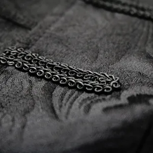Detailed view of men's vintage coat trim, featuring black braided embroidery and rich texture.