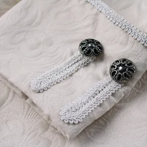 Detailed view of men's vintage coat cuff with intricate white braided trim and metallic buttons.