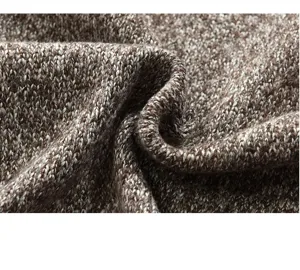 Close-up detail of mens brown white knitted sweater fabric showing fine texture and soft weave.