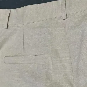 Close-up detail of men casual trousers waistband and pocket, showing fine fabric texture.