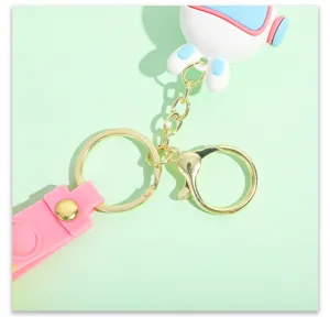 Close-up of cute cartoon space rabbit keychain with gold metal ring and pink strap detail.