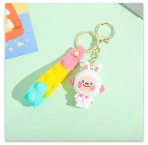 Close-up detail of cute cartoon astronaut rabbit keychain with colorful pop-it silicone strap.