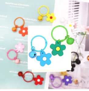 Detailopname van kleurrijke macaron bloem sleutelhangers met schattige belletjes voor tassen.