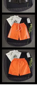 Detailed view of casual orange sports shorts with side stripes, comfortable loose fit.