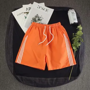 Orange casual sports shorts for men and women, summer loose five-point beach shorts with white stripes.