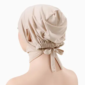 Vue détaillée du bonnet en coton mercerisé avec lien réglable et trous pour les oreilles.