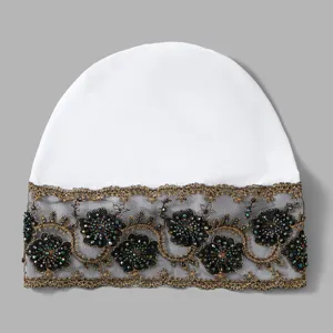 Detail view of women white beanie hat with black lace gold beaded floral trim decoration.