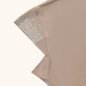 Detailed view of taupe knit headscarf featuring sparkling rhinestone embellishments along the edge.