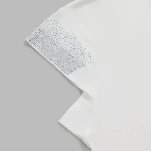 White fabric garment detail close-up featuring sparkling rhinestone embellishments for women.