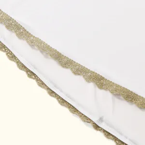 Close-up detail of white fabric with elegant gold embroidery lace trim, exquisite design.