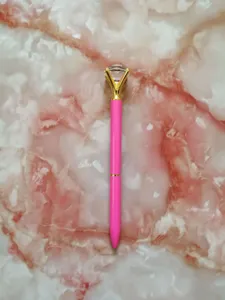 Close-up of a pink ballpoint pen with a large sparkling crystal diamond top