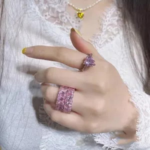 Set aus funkelnden rosa Herz- und rechteckigen Zirkonia-Ringen an der Hand eines Models