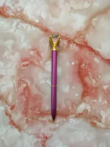 Close-up of a purple metal ballpoint pen topped with a large sparkling clear crystal