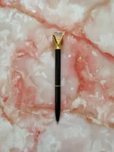 Close-up of elegant black ballpoint pen featuring a large sparkling diamond top