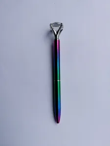 Macro detail of rainbow metal ballpoint pen with a large sparkling crystal diamond top.