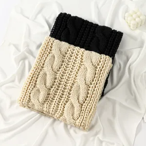 Nahaufnahme eines dicken Zopfmuster Winterschals in Schwarz und Beige. Kuschelig und warm.