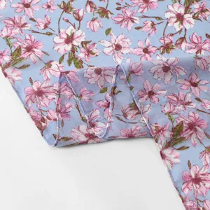 Chiffon fabric material close-up view with delicate pink floral print on light blue background.
