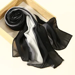 Detalle de bufanda larga degradada de gasa, hijab elegante negro gris blanco con perlas.