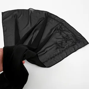 Black chiffon long scarf featuring delicate tone-on-tone bow embroidery pattern close up view.