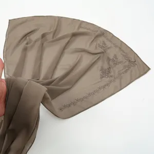 Chiffon scarf detail showing delicate bow embroidery, elegant women fashion head wrap.