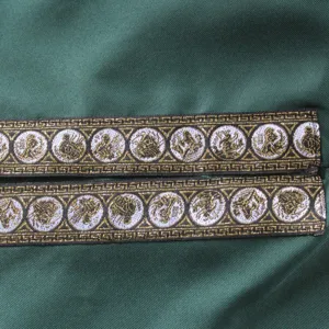 Close up detail of medieval costume fabric with gold woven trim and circular medallion pattern.