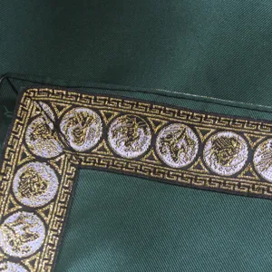 Green fabric medieval costume detail with gold Greek key and Medusa pattern woven trim