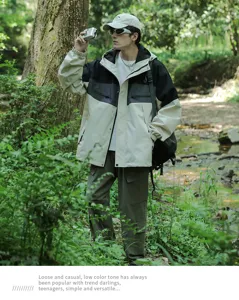 Dettaglio giacca outdoor con design color-block e cappuccio nella foresta naturale.