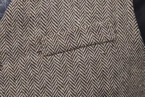 Herren Fischgrät Tweed Weste Detailaufnahme, klassischer brauner Stoff mit Taschendesign.