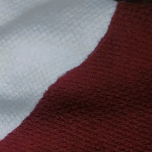 Gros plan sur le détail du tissu d'un cardigan pull tricoté pour homme blanc et bordeaux.