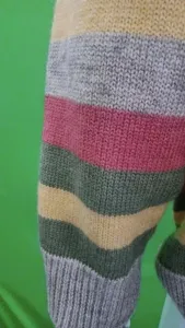 Primo piano sui dettagli della manica di un maglione lavorato a maglia a righe colorate.