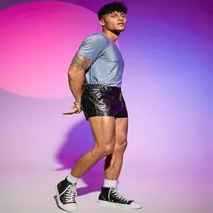Vista dettagliata dei pantaloncini in pelle nera da uomo abbinati a top e sneakers.