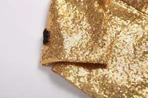 Gros plan detail manche blazer homme sequins dores montrant texture brillante et boutons noirs.