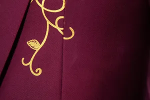 Burgundy suit jacket detail showing gold foil vine print on premium twill fabric.