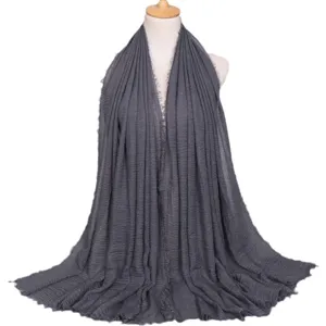 Sciarpa lunga tinta unita stropicciata in cotone e lino da donna con bordo a frange su display manichino.