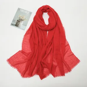 Red crinkled linen scarf detail showing delicate fringe and soft fabric texture closeup.