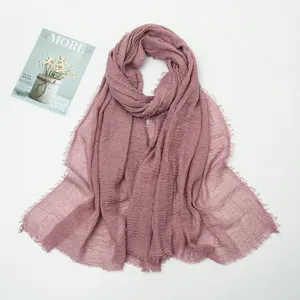 Detailed shot of mauve crinkled linen scarf with frayed edges, soft texture and elegant drape.