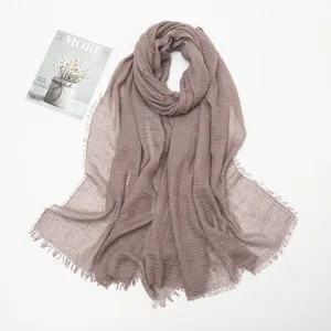 Close-up detail of the crumpled cotton-linen scarf featuring delicate fringed edges and soft texture.